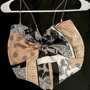 A tied back Just Polly New York crop top. In the color gold, white and black.